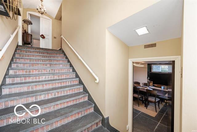 staircase with tile patterned flooring and a notable chandelier