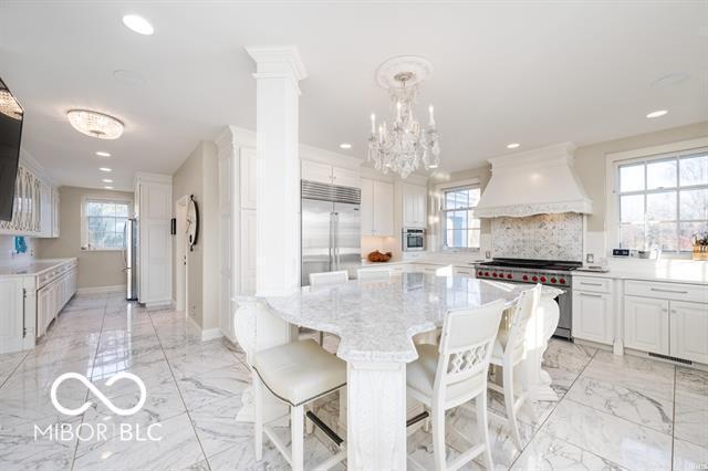 kitchen featuring pendant lighting, a center island, high quality appliances, premium range hood, and white cabinetry