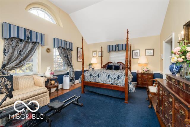 carpeted bedroom with vaulted ceiling and multiple windows