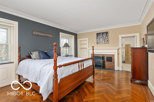 bedroom featuring a fireplace, parquet flooring, and crown molding