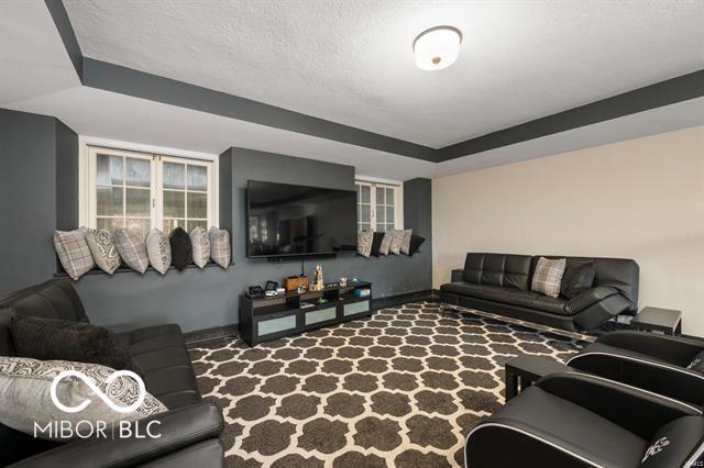 living room featuring a raised ceiling and a textured ceiling