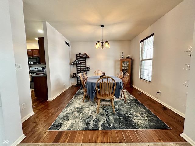 dining area featuring dark wood-type flooring and a notable chandelier