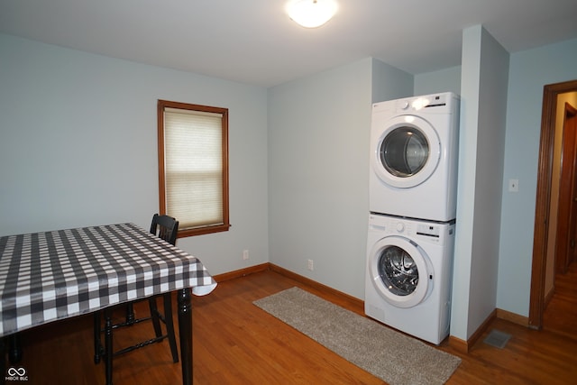 laundry area with stacked washer / drying machine and wood-type flooring