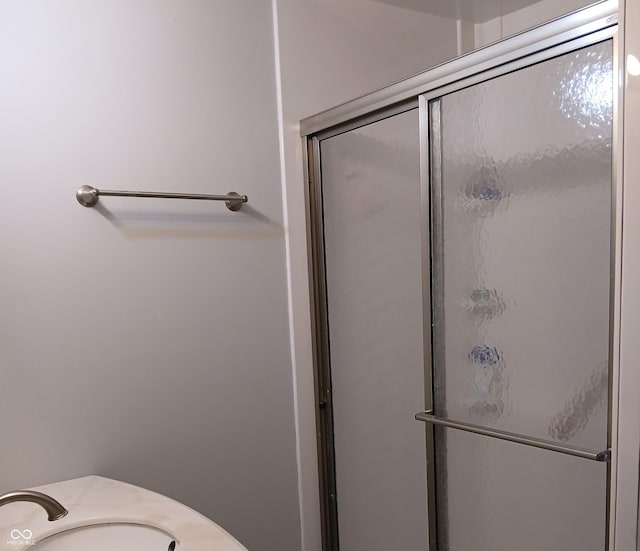 bathroom featuring a shower with door and sink