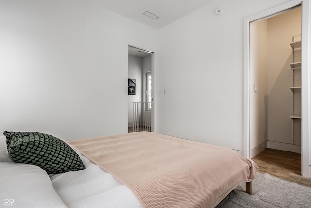 bedroom with a walk in closet and hardwood / wood-style flooring