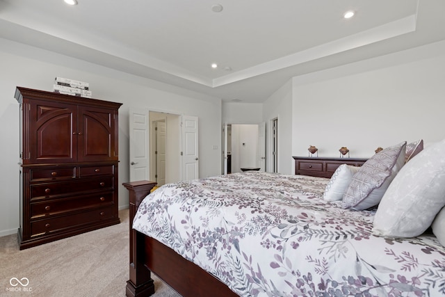 bedroom with recessed lighting, a raised ceiling, and light colored carpet