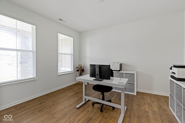 office space with visible vents, plenty of natural light, baseboards, and wood finished floors