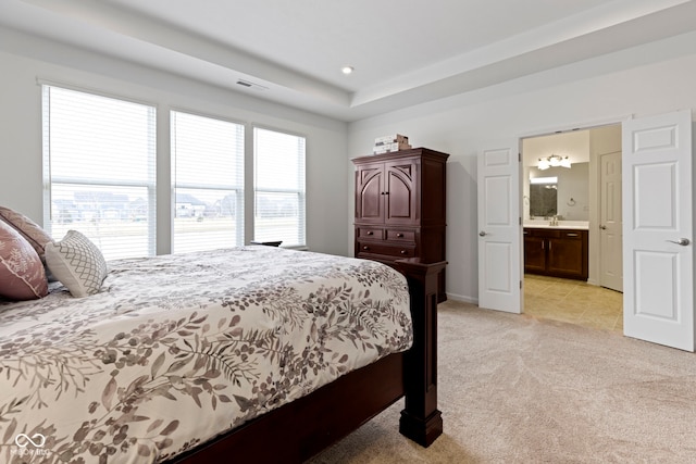 bedroom featuring ensuite bath, visible vents, and light colored carpet