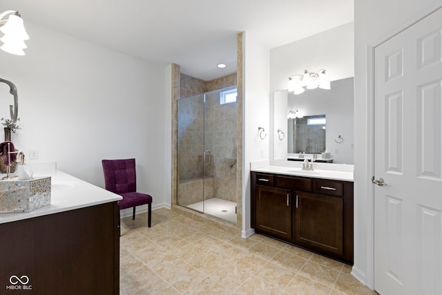 bathroom featuring a sink, a shower stall, baseboards, and two vanities