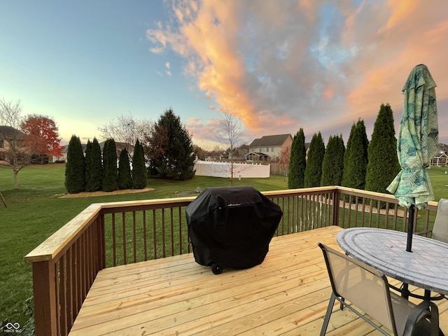 deck at dusk with area for grilling and a yard