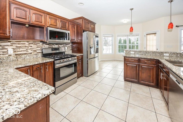 kitchen with hanging light fixtures, light stone countertops, tasteful backsplash, light tile patterned flooring, and stainless steel appliances