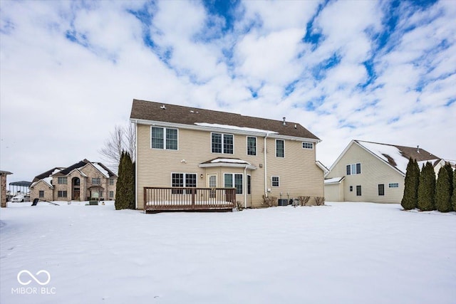 snow covered back of property featuring a deck