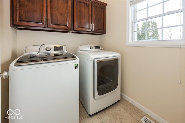 laundry room featuring cabinets, washing machine and dryer, and light tile patterned floors