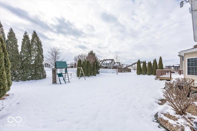 snowy yard featuring a playground