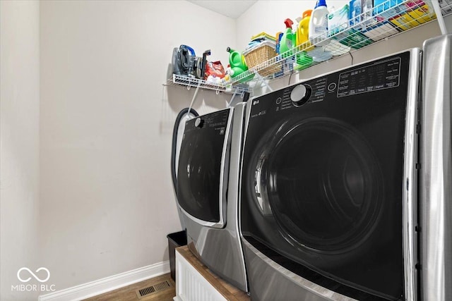 laundry room with separate washer and dryer and hardwood / wood-style floors