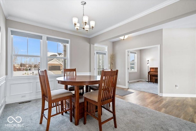 dining area featuring ornamental molding, a healthy amount of sunlight, and a notable chandelier