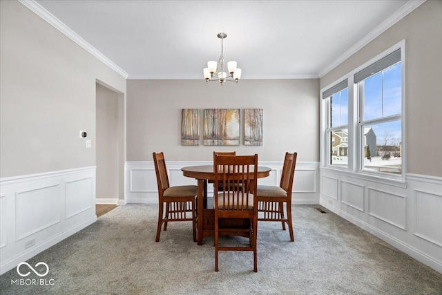 carpeted dining area featuring ornamental molding and a chandelier