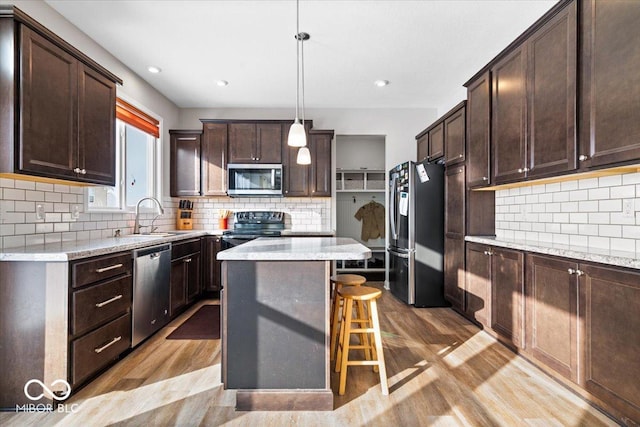 kitchen featuring pendant lighting, appliances with stainless steel finishes, a center island, sink, and a breakfast bar area