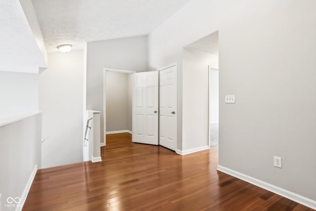 unfurnished bedroom featuring vaulted ceiling and dark hardwood / wood-style floors