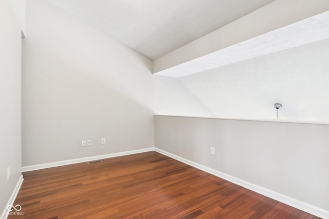 bonus room with vaulted ceiling and dark wood-type flooring