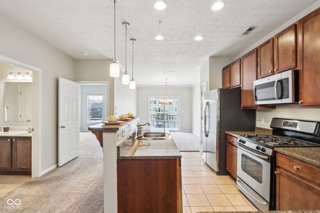 kitchen with a kitchen island with sink, hanging light fixtures, light colored carpet, and stainless steel appliances