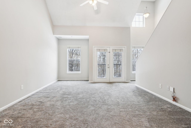 unfurnished living room with a wealth of natural light, ceiling fan, french doors, and carpet floors