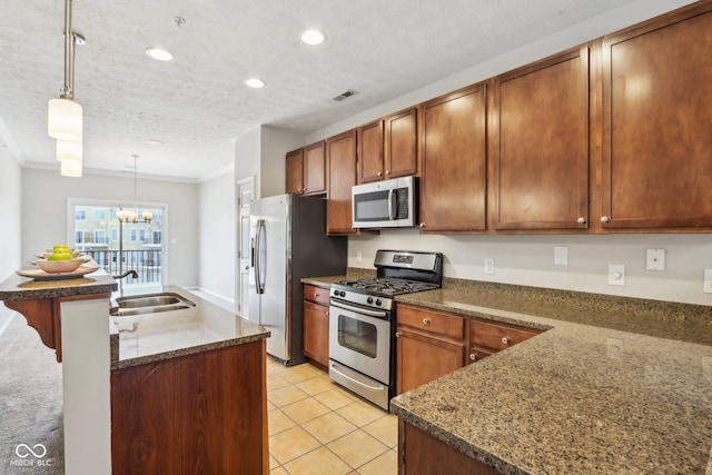 kitchen with sink, an inviting chandelier, pendant lighting, a textured ceiling, and appliances with stainless steel finishes