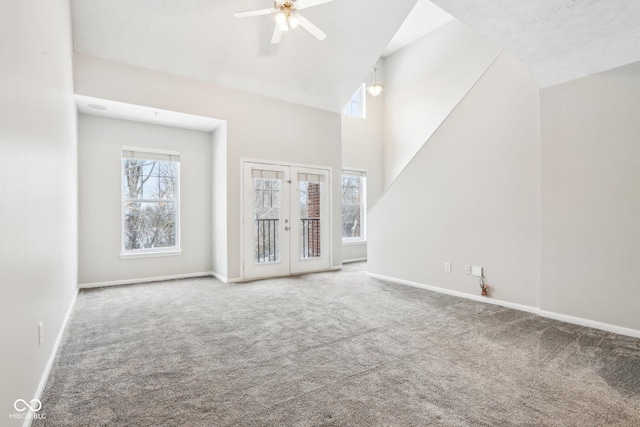 unfurnished living room featuring carpet flooring, ceiling fan, french doors, and a towering ceiling