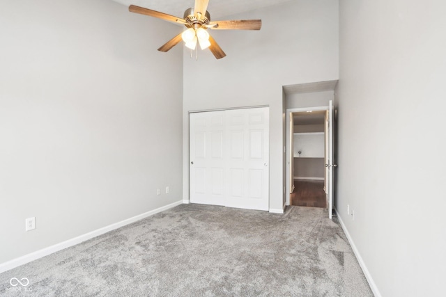 unfurnished bedroom with ceiling fan, a closet, carpet, and high vaulted ceiling