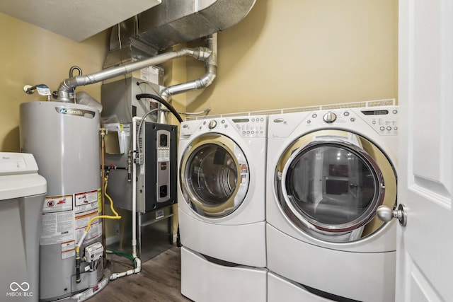 washroom with dark hardwood / wood-style flooring, gas water heater, and washing machine and clothes dryer