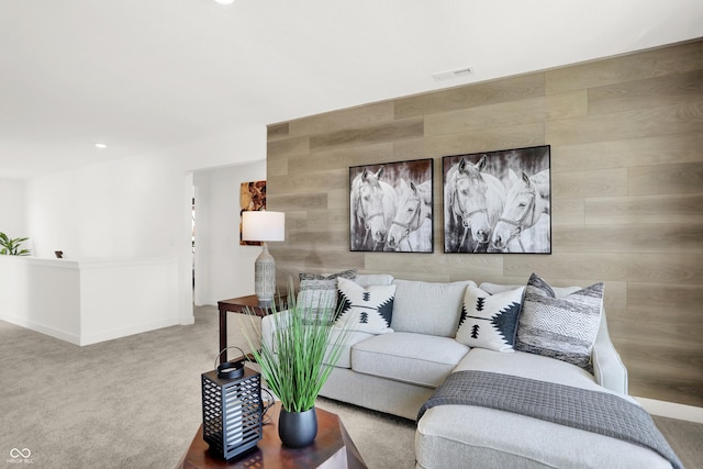 carpeted living room featuring wood walls