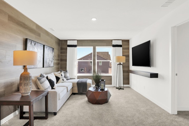 carpeted living room with wood walls