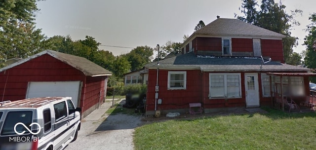 view of front of house with a garage, an outbuilding, and a front yard