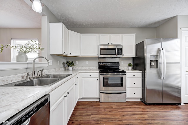 kitchen featuring white cabinets, appliances with stainless steel finishes, a textured ceiling, and sink