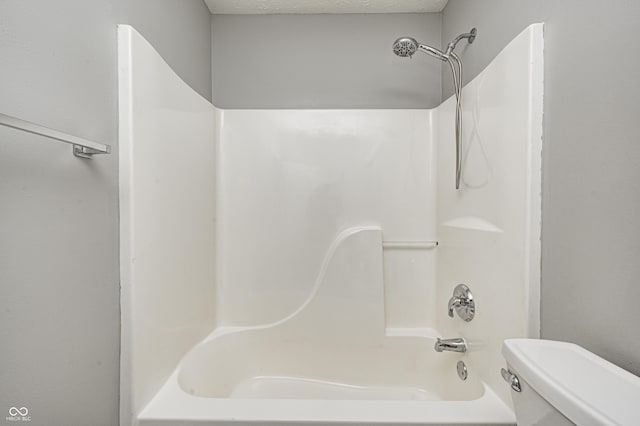 bathroom with toilet, shower / bath combination, and a textured ceiling