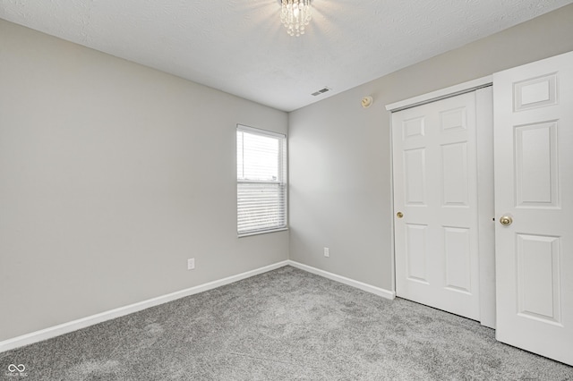 unfurnished bedroom with light carpet, a textured ceiling, and a closet