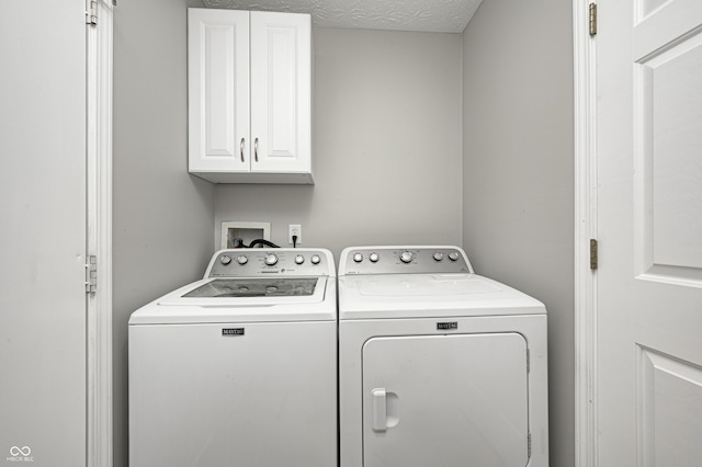 washroom with separate washer and dryer, cabinets, and a textured ceiling