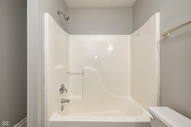 bathroom featuring toilet, washtub / shower combination, and a textured ceiling