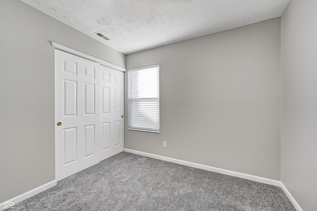 unfurnished bedroom with a textured ceiling, carpet floors, and a closet