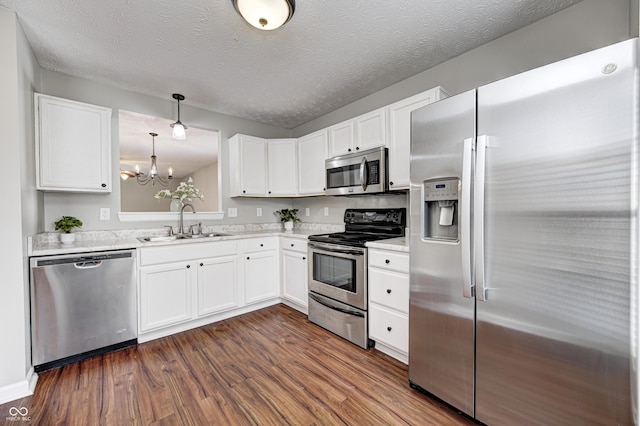 kitchen with decorative light fixtures, stainless steel appliances, white cabinetry, and sink