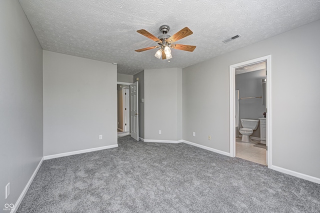 unfurnished bedroom with connected bathroom, ceiling fan, light colored carpet, and a textured ceiling