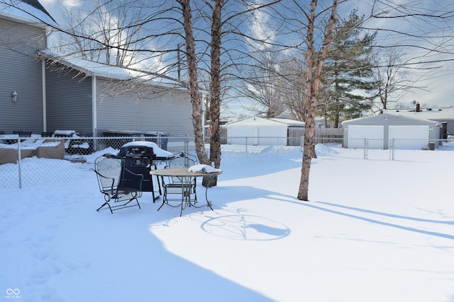 snowy yard featuring a garage and an outdoor structure