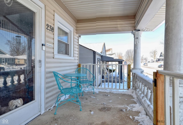 snow covered back of property featuring a porch