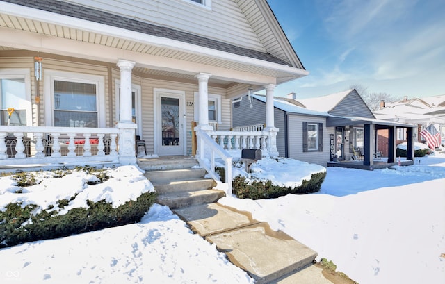 snow covered property entrance with covered porch