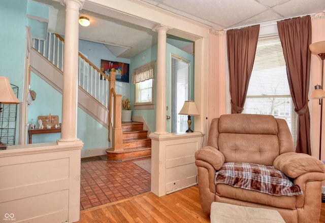 living area with a drop ceiling, light hardwood / wood-style floors, and a wealth of natural light