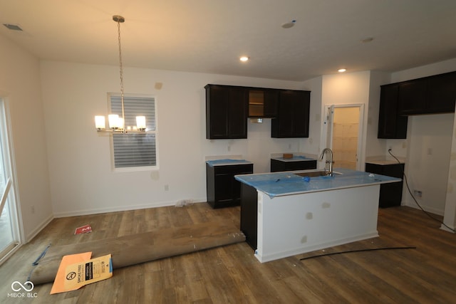 kitchen featuring sink, a chandelier, hanging light fixtures, dark hardwood / wood-style flooring, and a kitchen island with sink