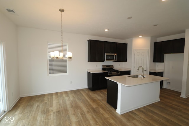 kitchen with appliances with stainless steel finishes, sink, a center island with sink, and light hardwood / wood-style flooring