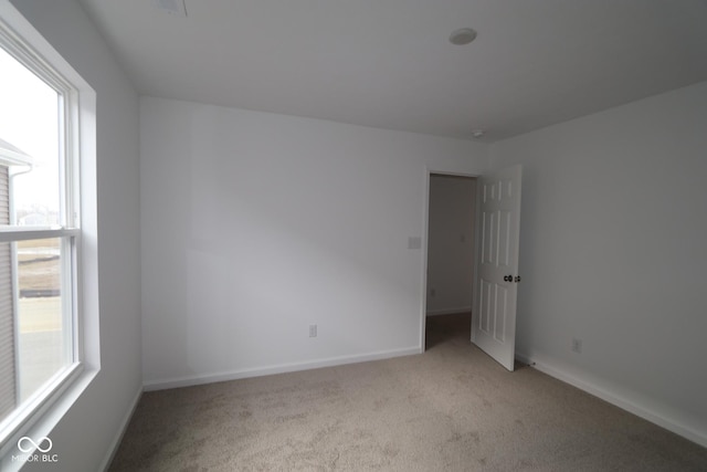 unfurnished room featuring light colored carpet and plenty of natural light