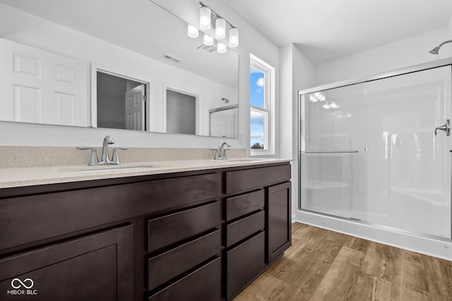 bathroom featuring a stall shower, visible vents, a sink, and wood finished floors