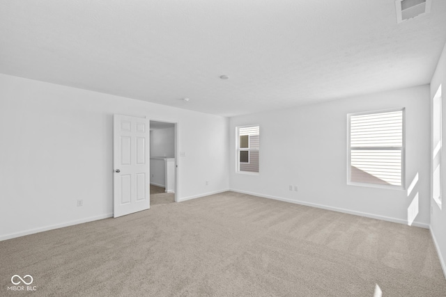 unfurnished room with light colored carpet, visible vents, and baseboards